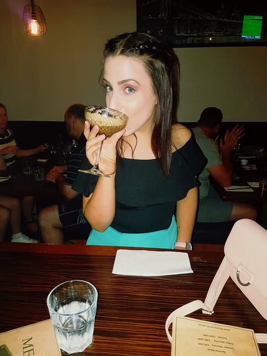 Woman drinking from a cocktail glass in a bar setting
