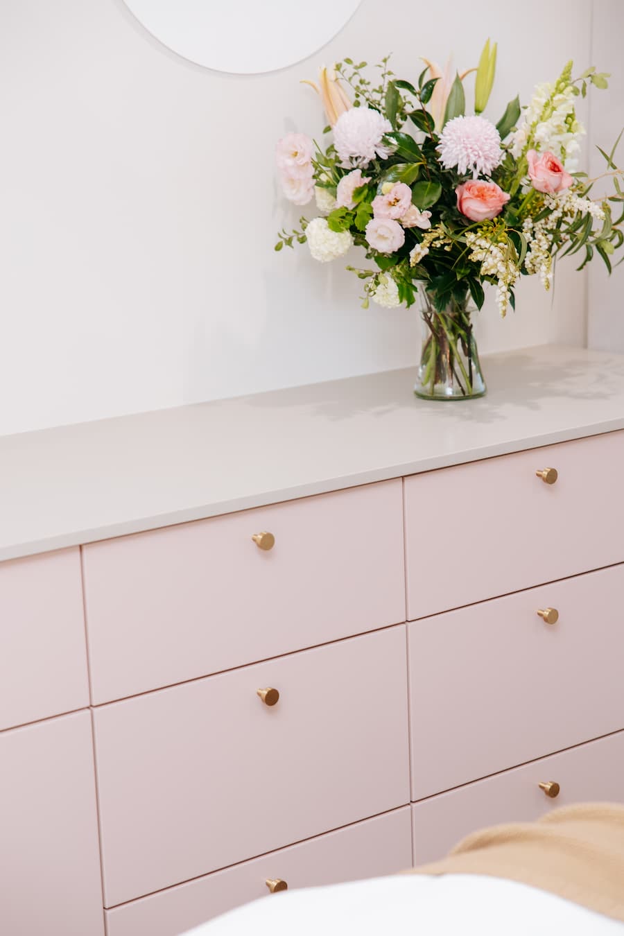 Pink dresser with a vase of flowers on a white surface at TGS Beauty & Skin salon in Perth