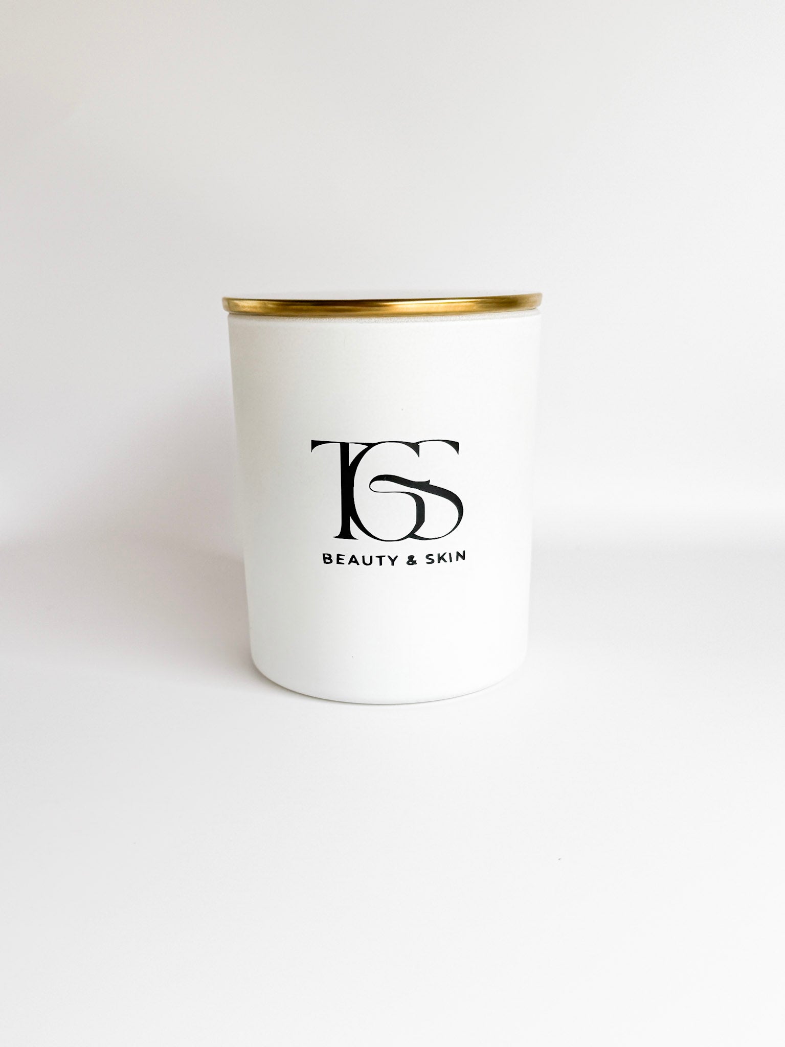 White candle jar with gold lid clearly showing branding and design.