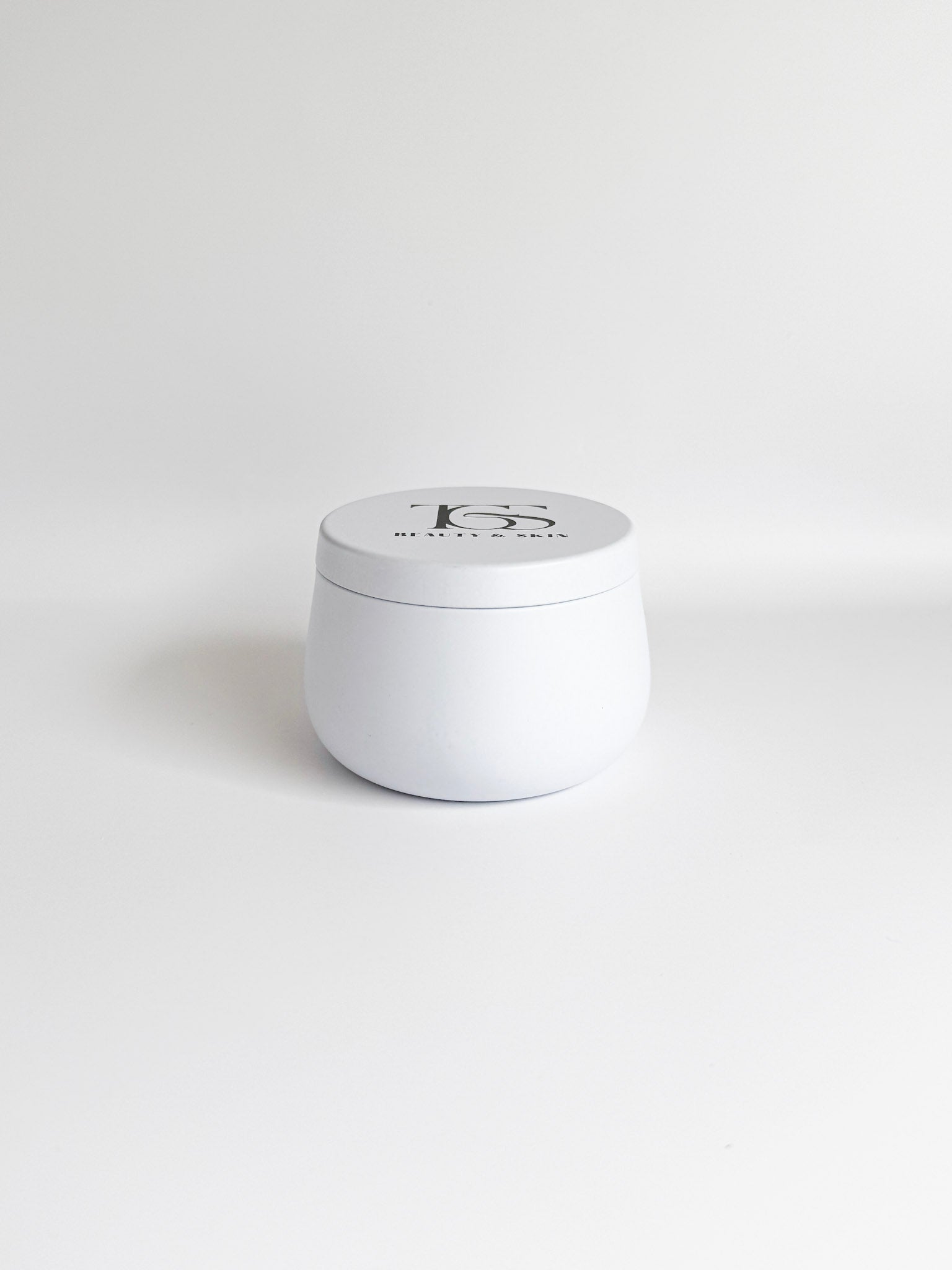 Small, white travel-sized candle in a tin container.