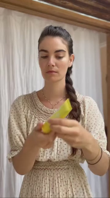 Woman demonstrating application of sunscreen product in neutral setting.