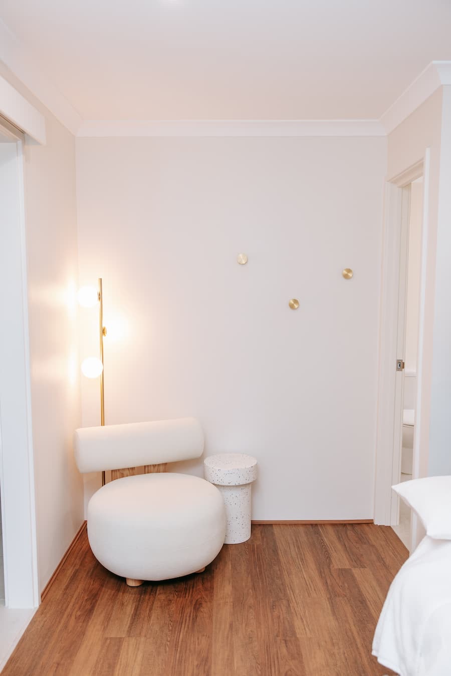 Modern interior with white ottomans and a lamp on a wooden floor.