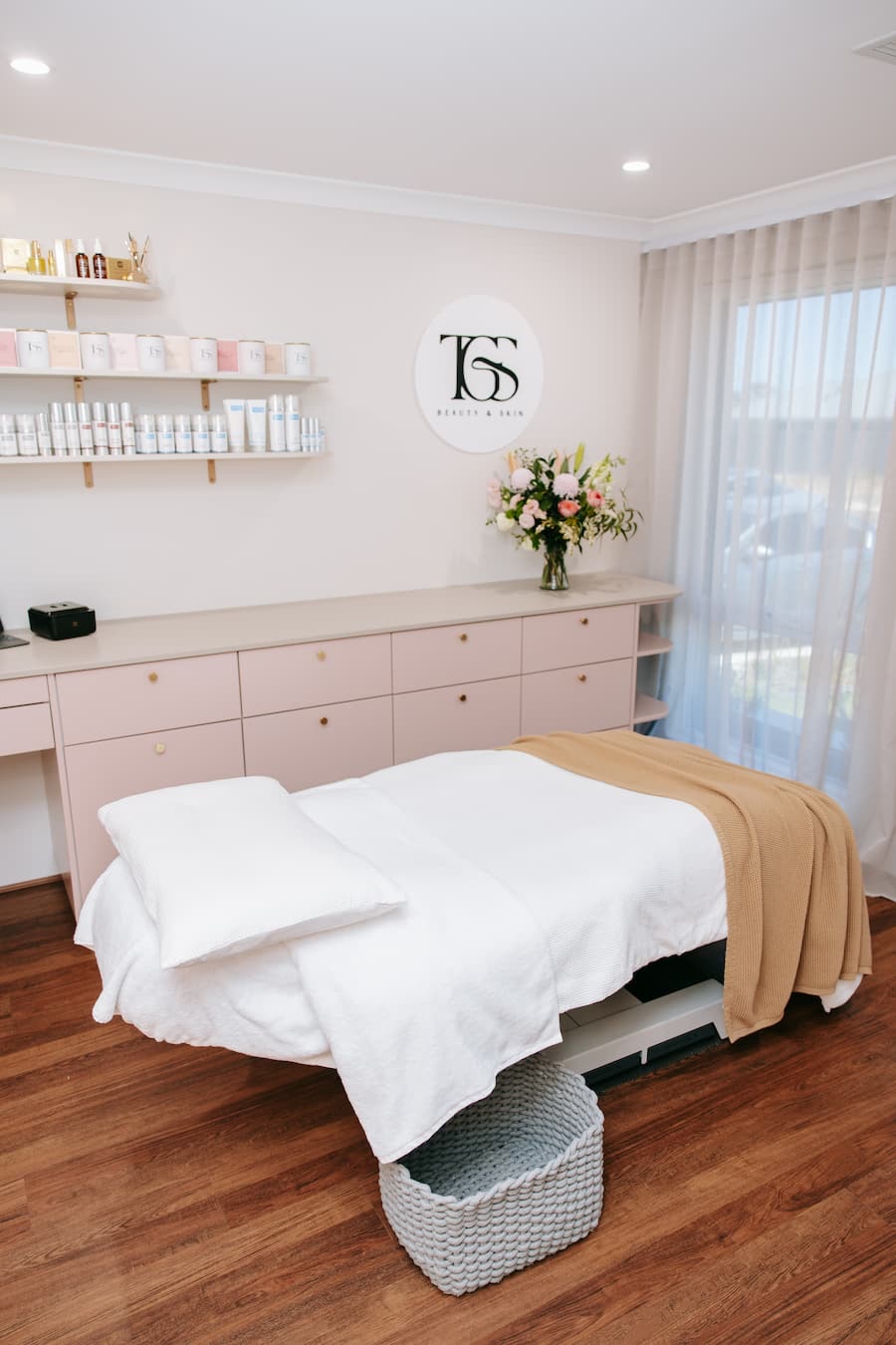 Spa or salon interior with a treatment bed, shelves with products, and a decorative wall sign.