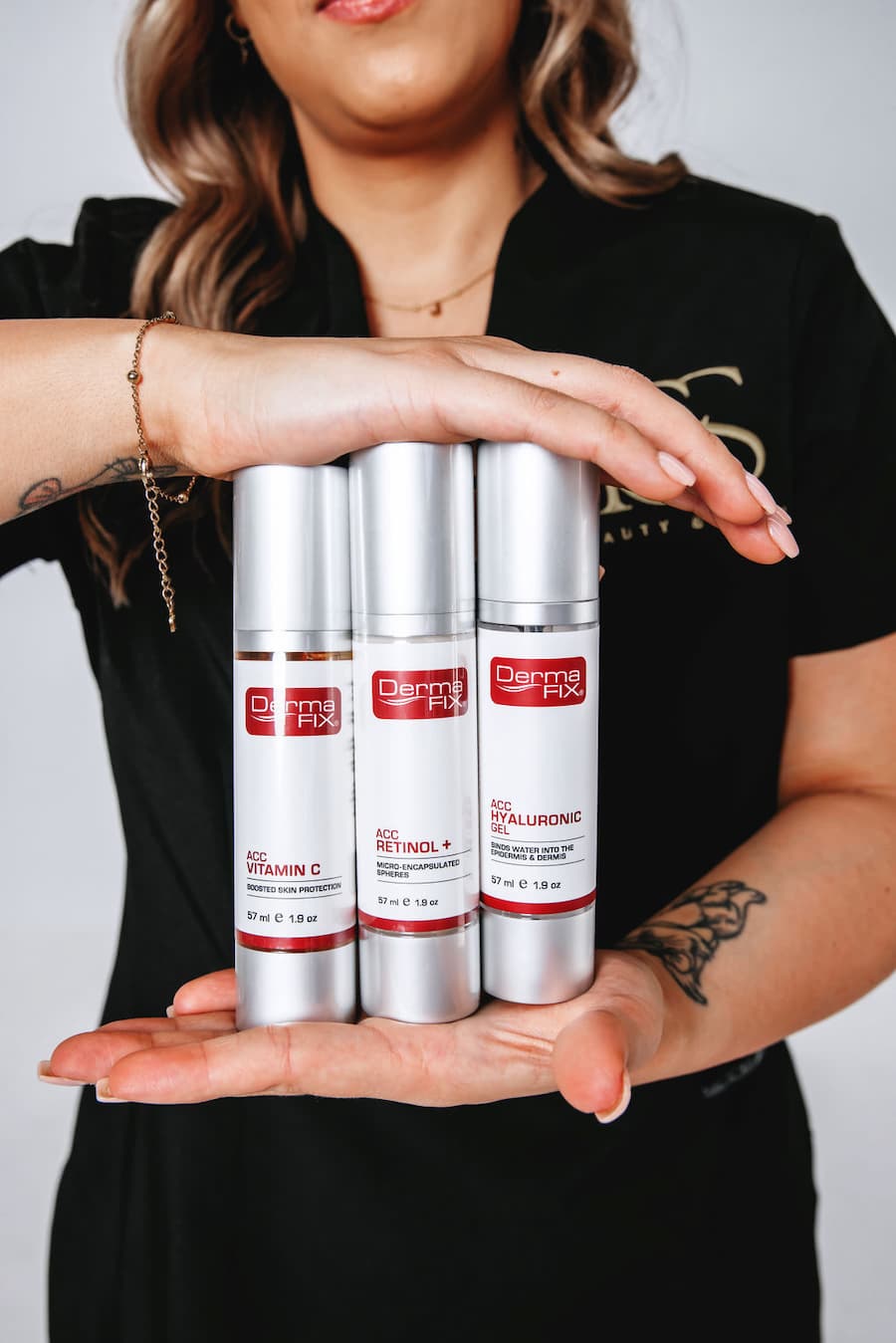 Person holding three skincare product bottles labeled 'Dermatix' against a neutral background at TGS Beauty & Skin in Perth