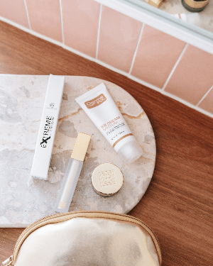 Mascara tube styled on a bathroom counter with beauty accessories.