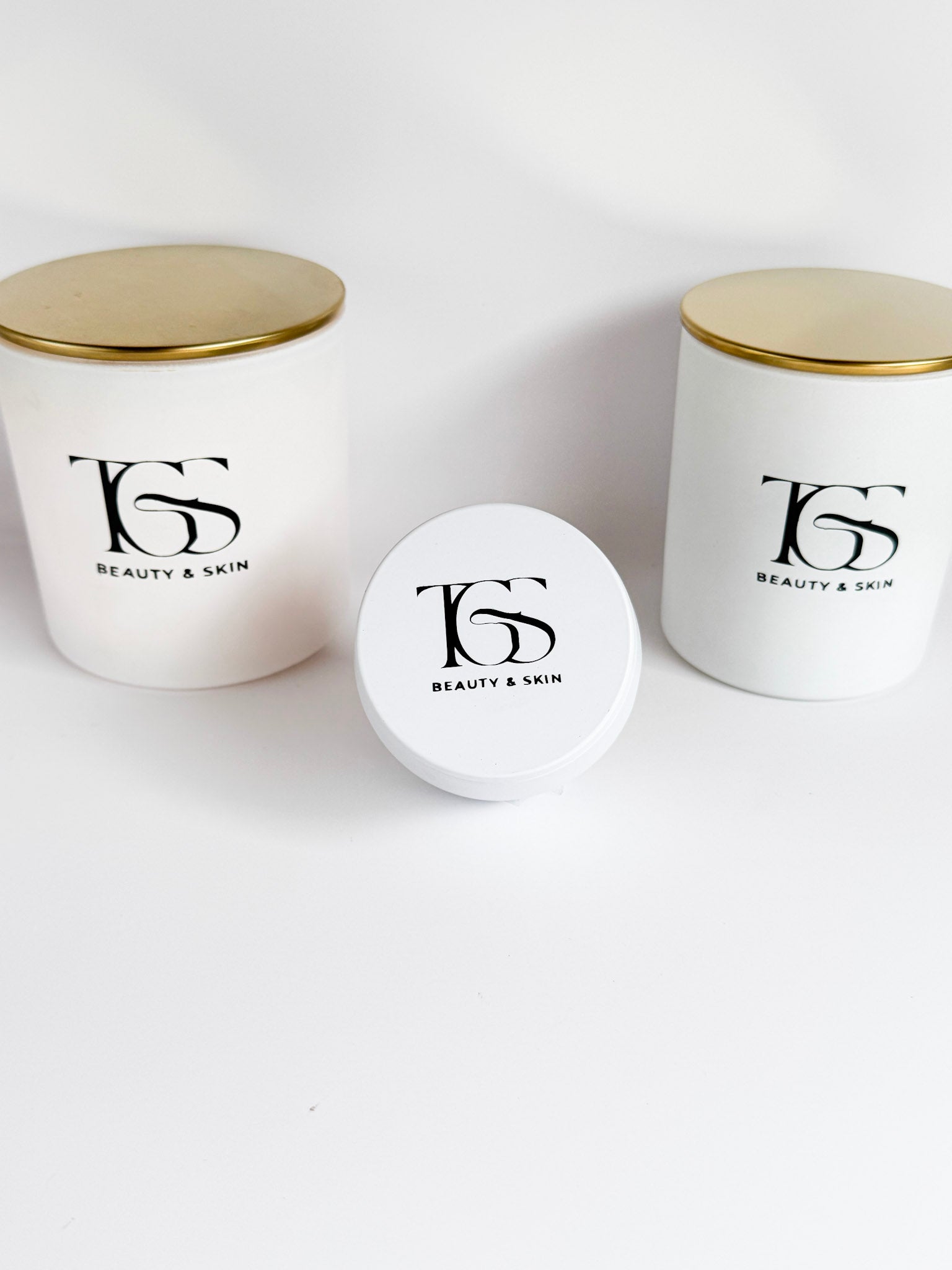  Group of white candles in various sizes with matching gold lids.