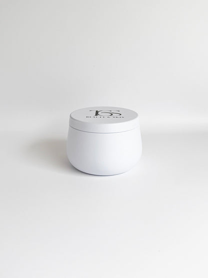 Small, white travel-sized candle in a tin container.
