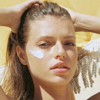 Close-up of woman’s face with sunscreen applied to cheeks.