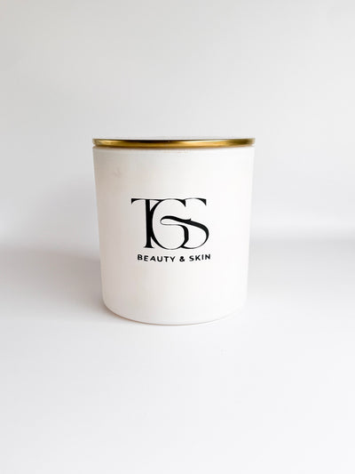 Close-up of candle highlighting the matte white jar and gold lid design.