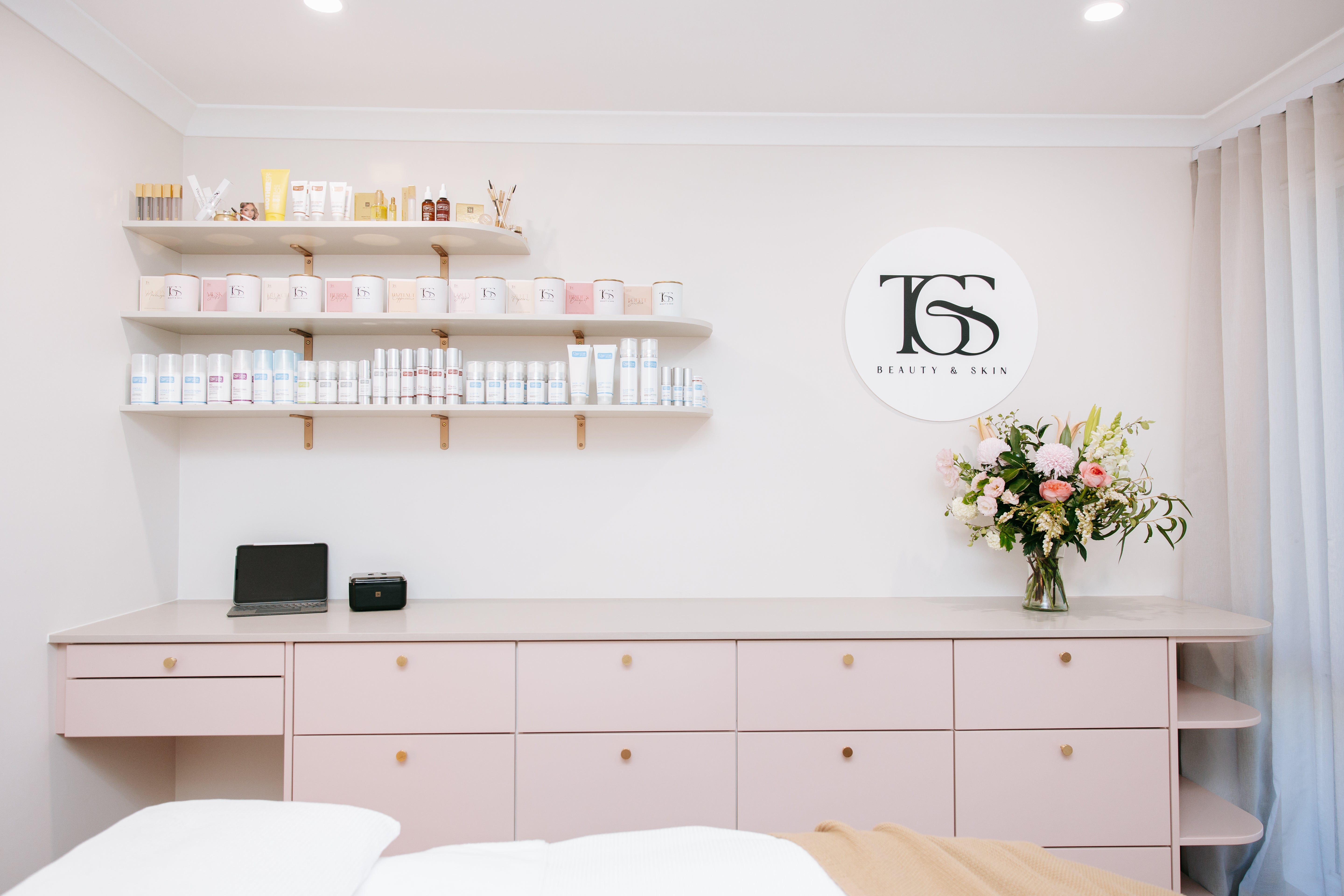 TGS Beauty & Skin salon interior with product display shelves, branded logo, and fresh flowers in Hammond Park Perth

